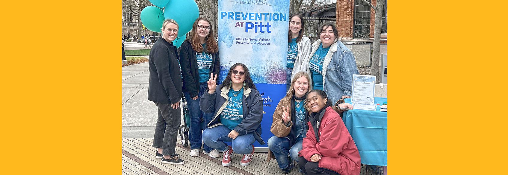 A photo of a group of people flashing the peace sign with a banner that says "Prevention at Pitt"
