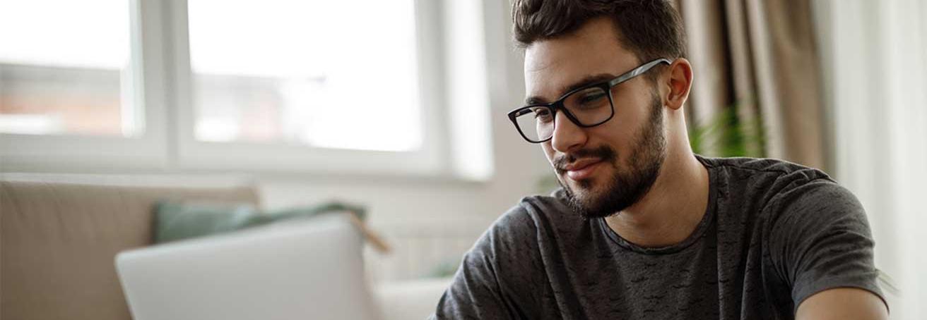 Man with glasses using a laptop computer in his home's living room